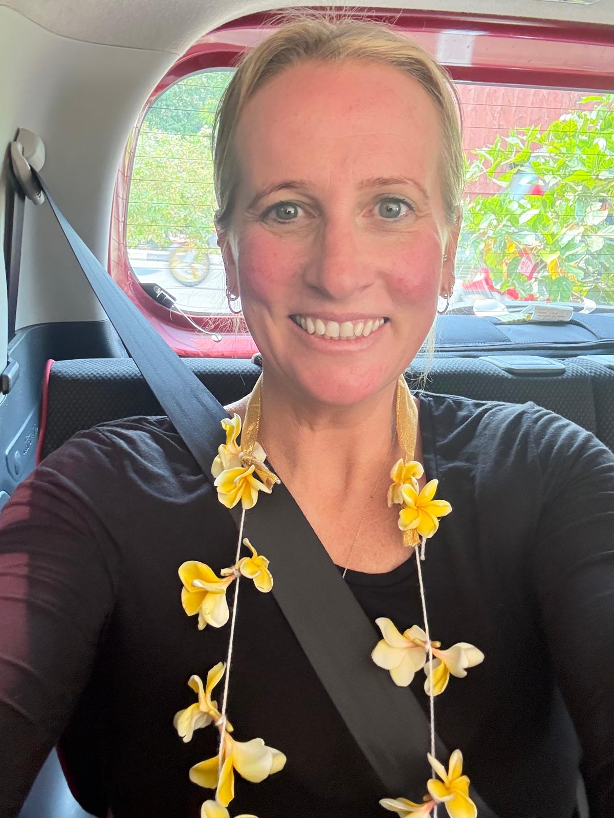 Sally's testimonial photo shows a guest smiling, wearing a frangipani flower garland on arrival in Sri Lanka