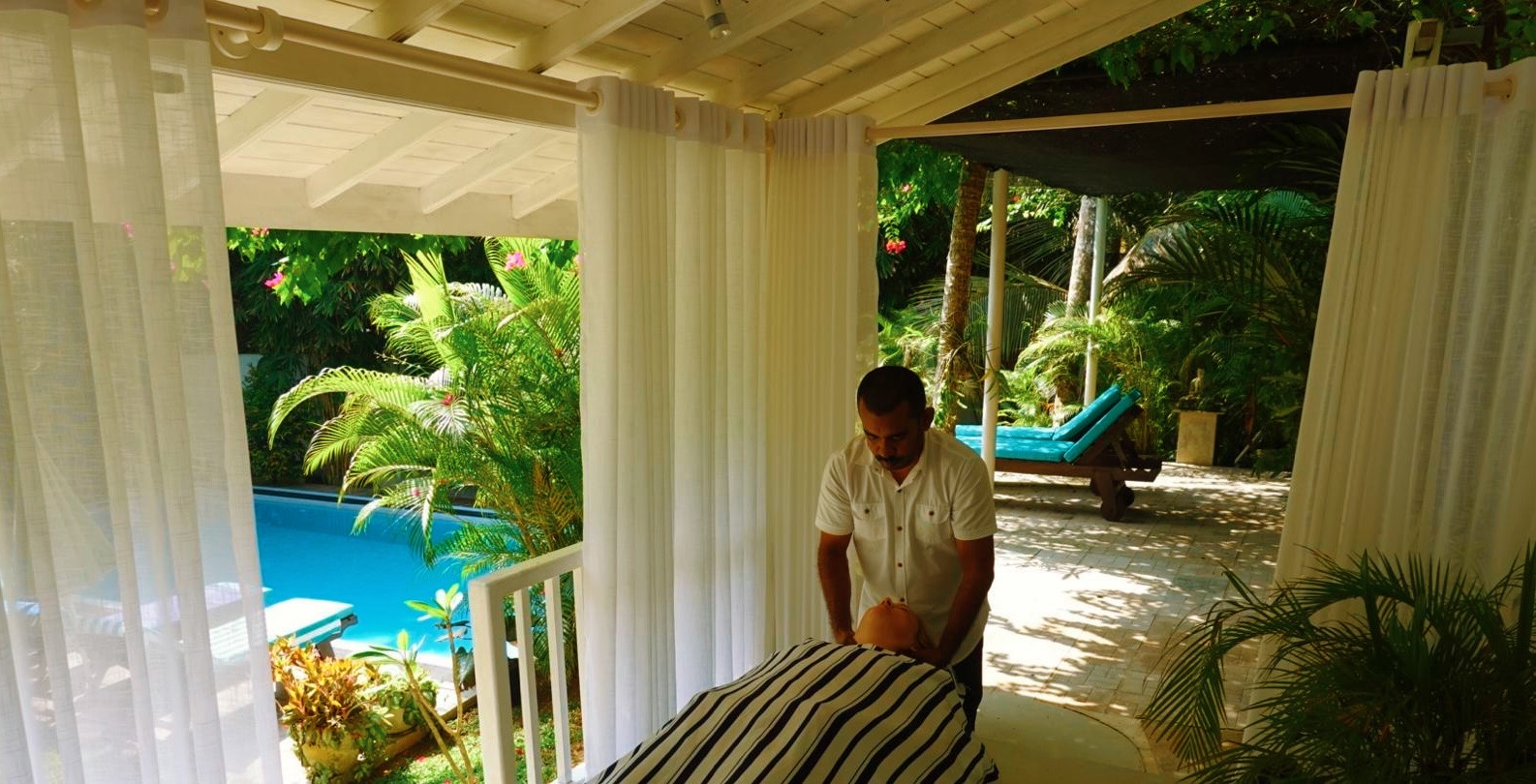Massage therapist working in an open-air pavilion beside the pool