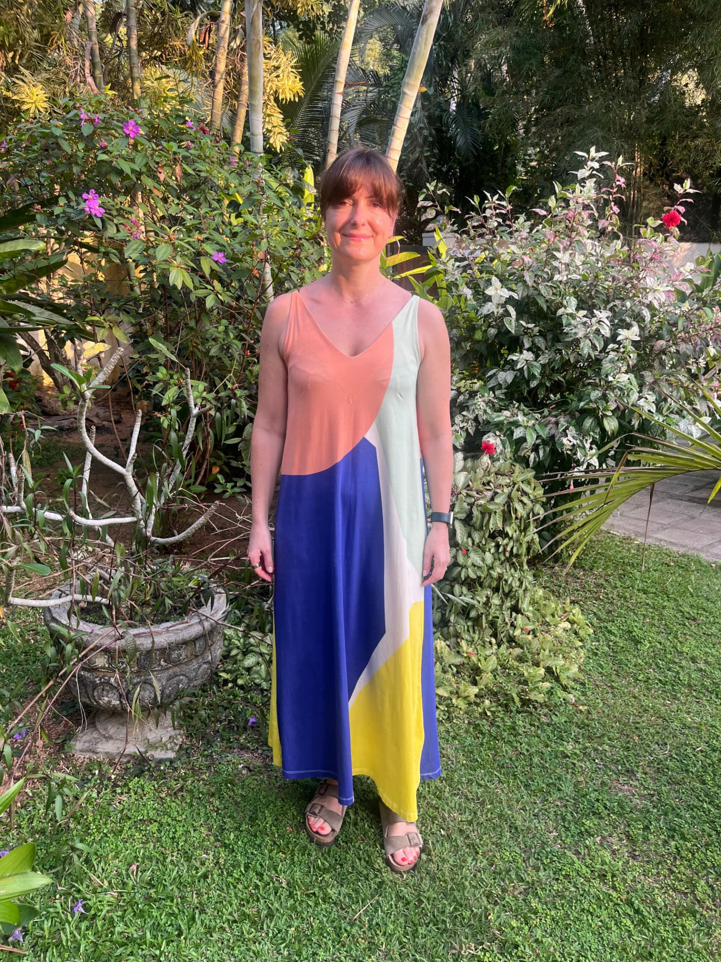 Nikki standing in a tropical garden wearing a long colour-block dress