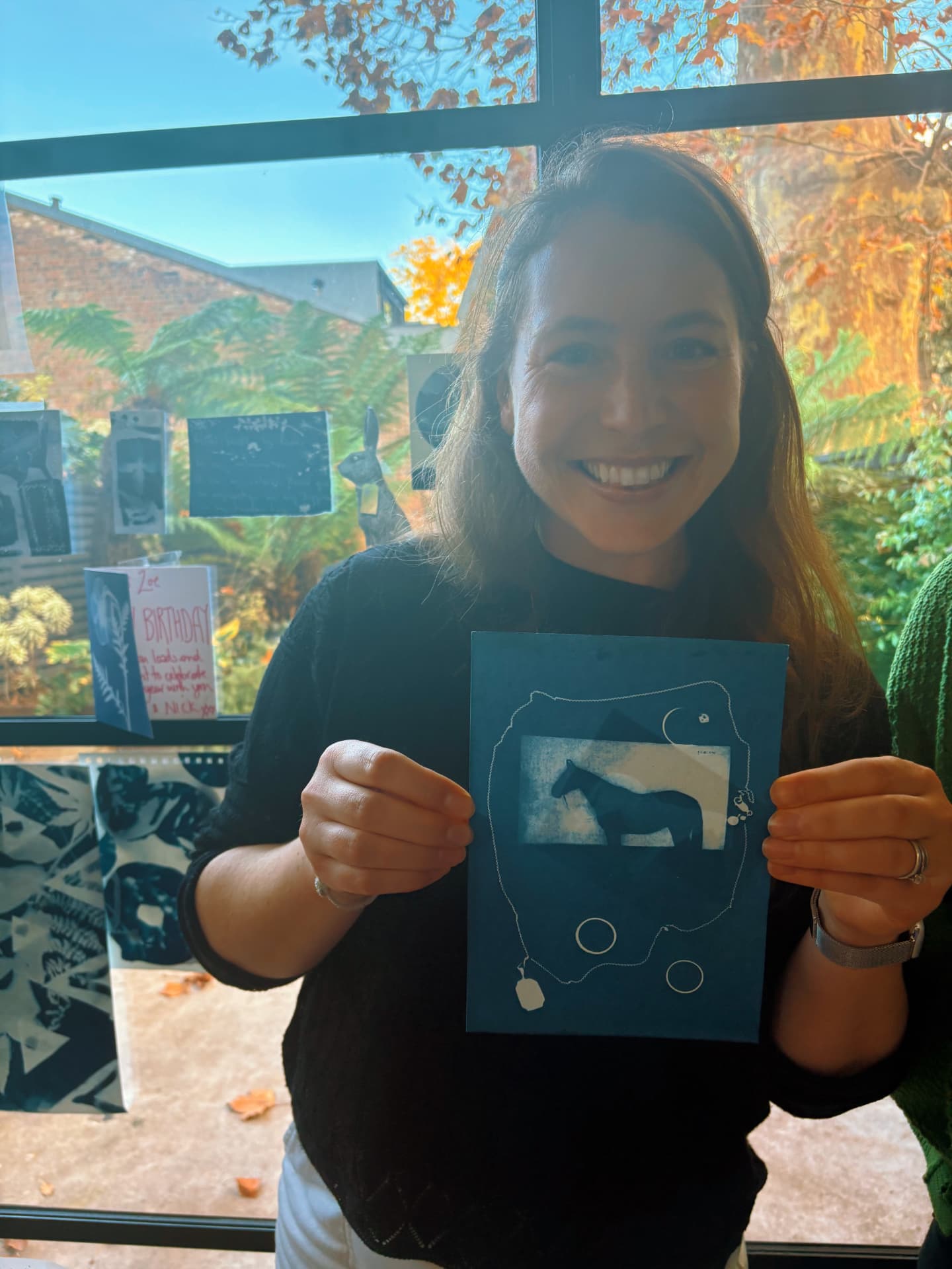 Woman holding a cyanotype artwork of a horse in a bright studio
